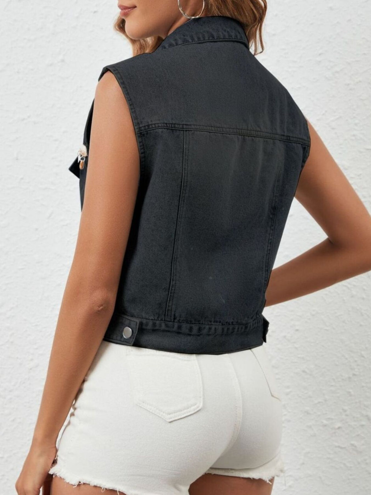 Black button-up denim vest by Trendsi, featuring classic design and metal buttons, worn over casual outfits.