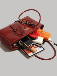 Leather shoulder bag with knot detail by Trendsi, featuring a sleek design and adjustable strap for stylish everyday use.