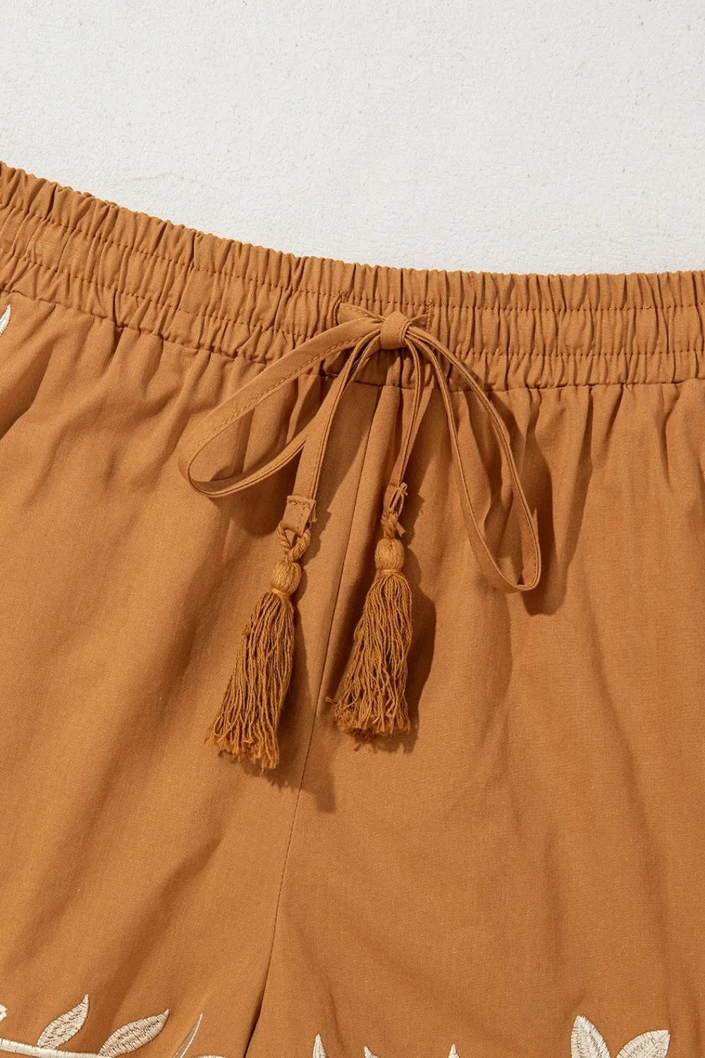 Embroidered boho casual shorts with tasseled drawstring and elastic waist in caramel color, featuring intricate embroidery details.