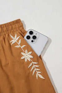 Embroidered boho-style casual shorts with tasseled drawstring and elastic waist, featuring trendy design and earthy caramel color.