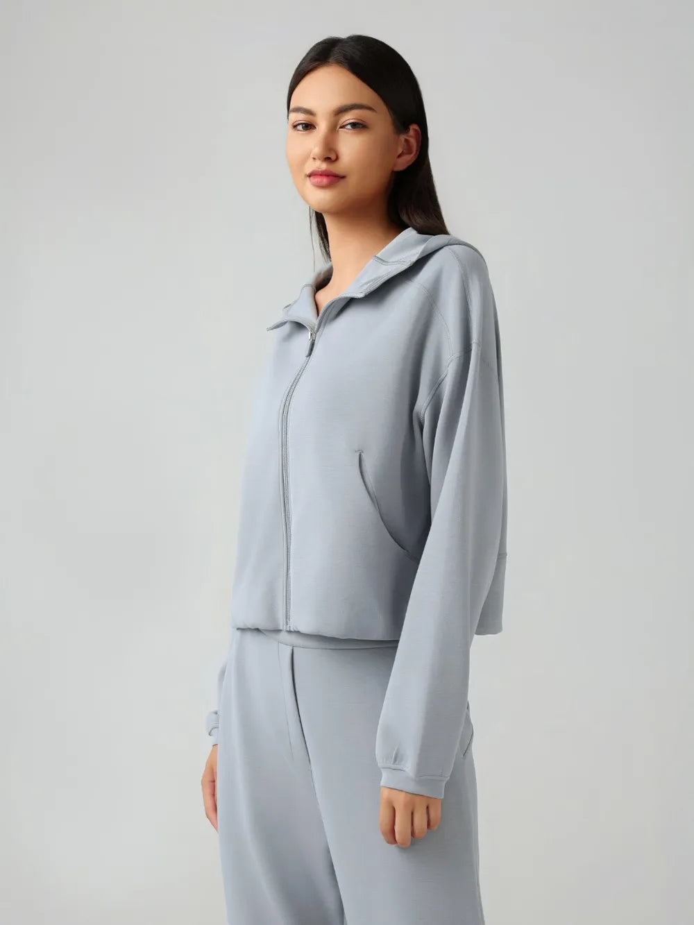 Trendsi Millennia zip-up active hoodie with dropped shoulders and hood, featuring a stylish, comfortable design.