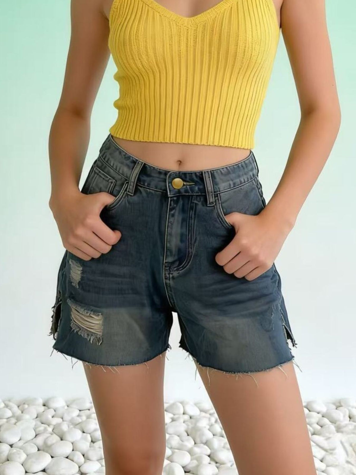 Distressed slit denim shorts by Trendsi featuring frayed hems and a casual fit, shown on a model in a stylish outdoor setting.