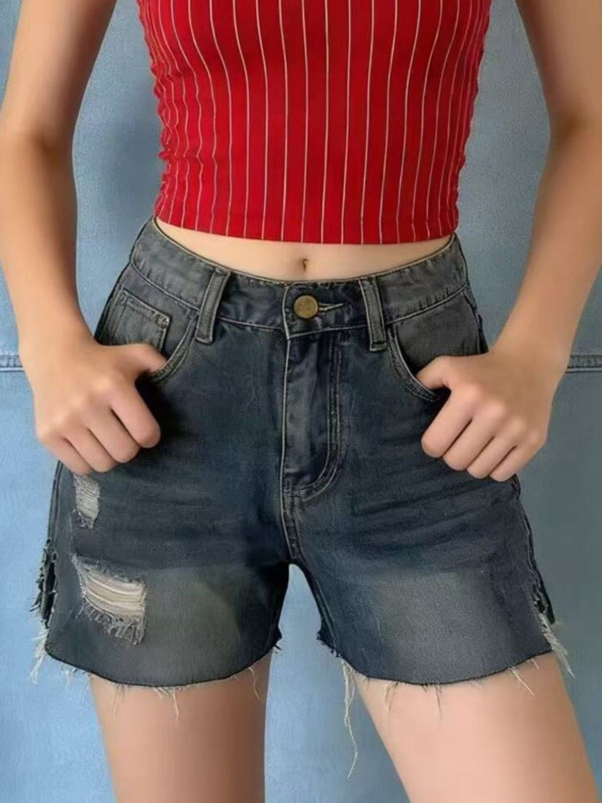 Distressed slit denim shorts by Trendsi featuring a frayed hem, high waist, and ripped details, styled for casual summer wear.