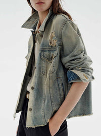 Distressed wash button-up denim jacket by Trendsi, featuring a casual fit with faded details and metal buttons.