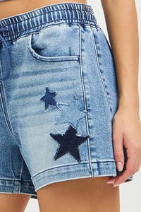 Risen elastic band slouchy denim shorts by Trendsi with star patch details, casual fit, and distressed blue fabric.