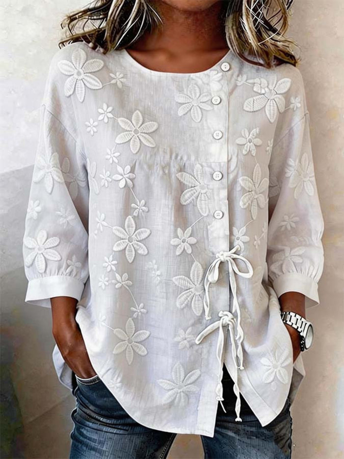Plus size white floral embroidered button-down shirt by Trendsi, showing intricate floral embroidery and classic collar design.