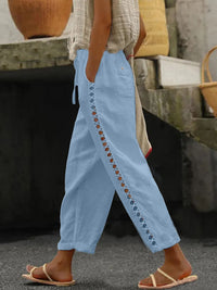 Hollow out trim cropped pants by Trendsi featuring a stylish cut-out design and a tailored fit, displayed in a fashion-forward setting.