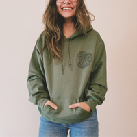 Olive green Monstera hoodie by VesperTwine featuring a tropical leaf design, made from soft fabric with a cozy fit.