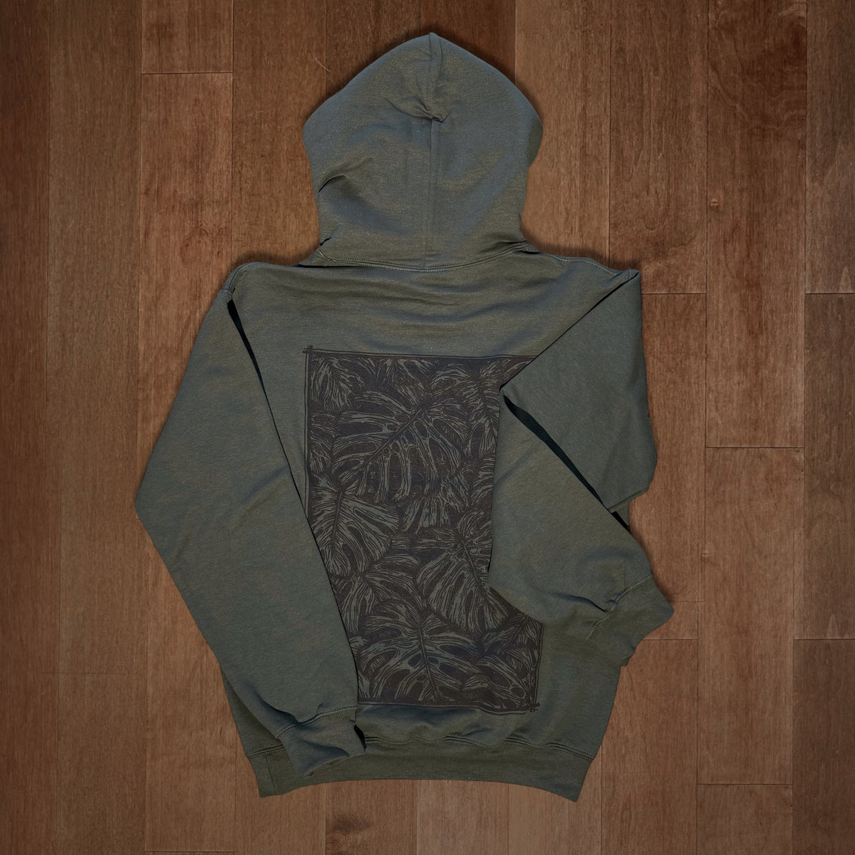 Olive green Monstera hoodie by VesperTwine featuring a large tropical leaf print on the front.