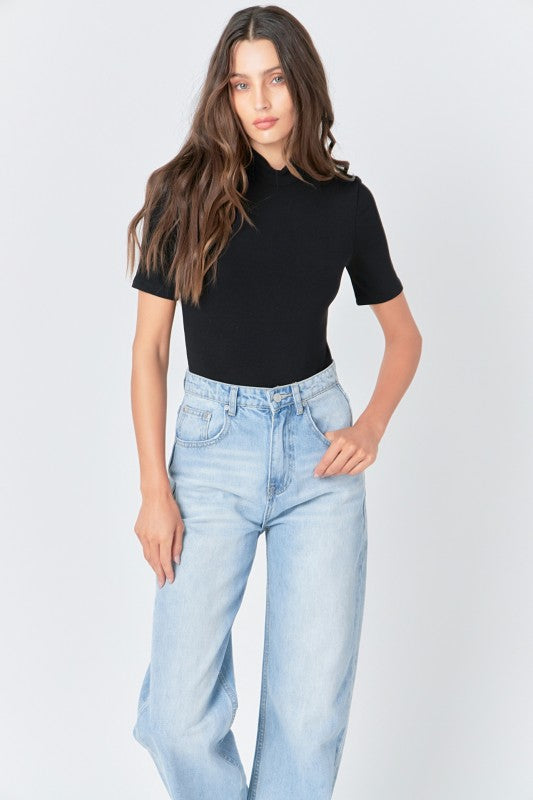 Soft black mock neck bodysuit by voglio.us, close-up of the fitted top with long sleeves and smooth fabric.