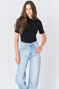 Soft black mock neck bodysuit by voglio.us, close-up of the fitted top with long sleeves and smooth fabric.