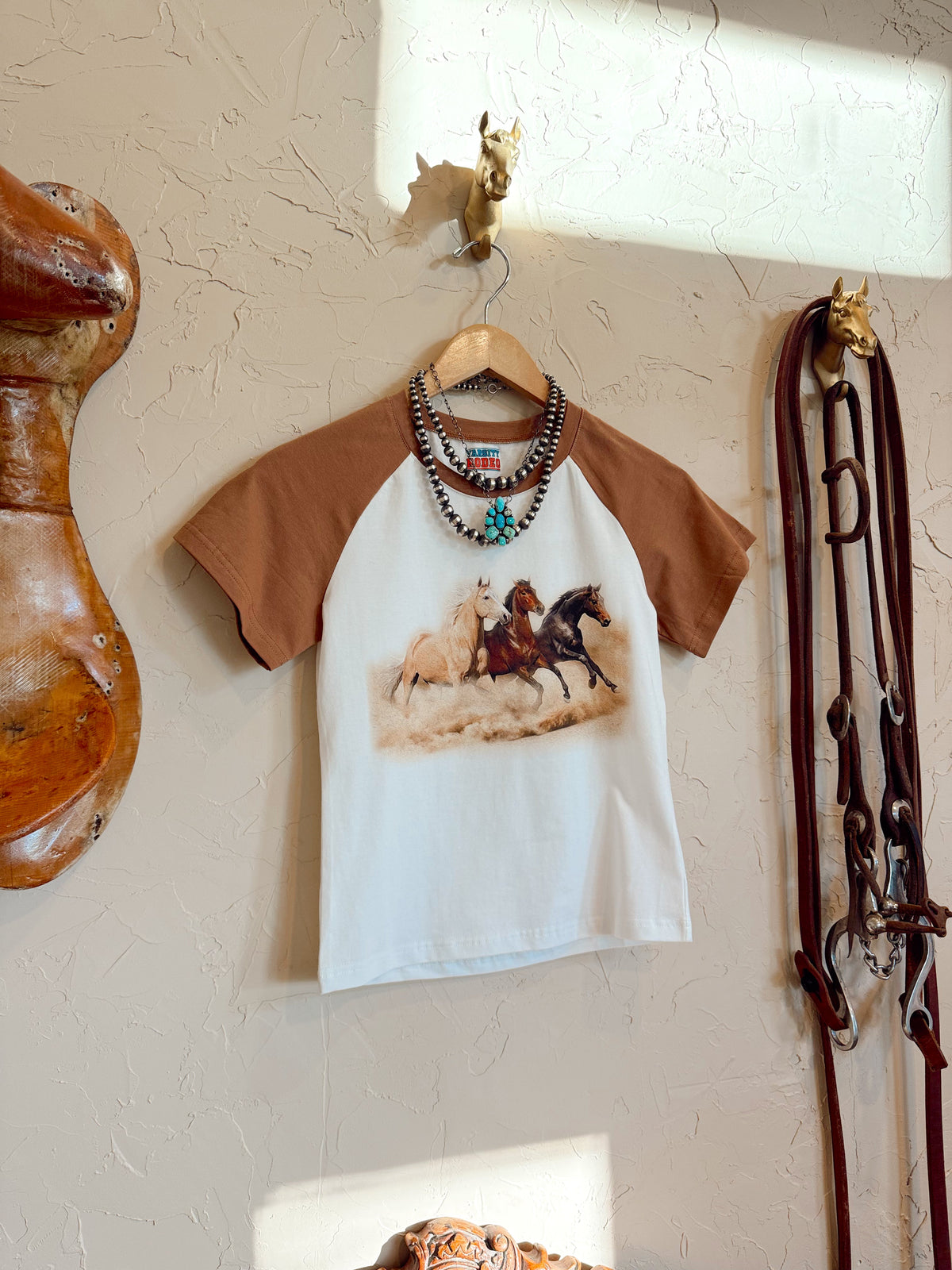 Western Vogue Boutique The Stampede Horses T-Shirt, casual Western-themed top featuring a horse graphic on soft fabric.
