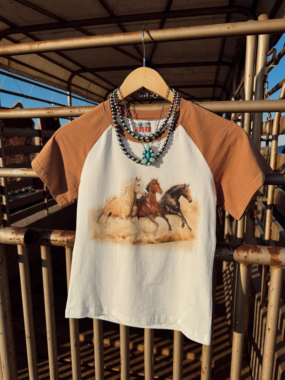 Western Vogue Boutique The Stampede Horses T-Shirt featuring a detailed horse graphic on a casual top.
