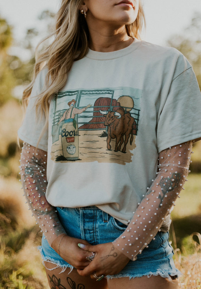 Western graphic top by Wild Cactus Boutique featuring a detailed rodeo scene design on a casual tee.
