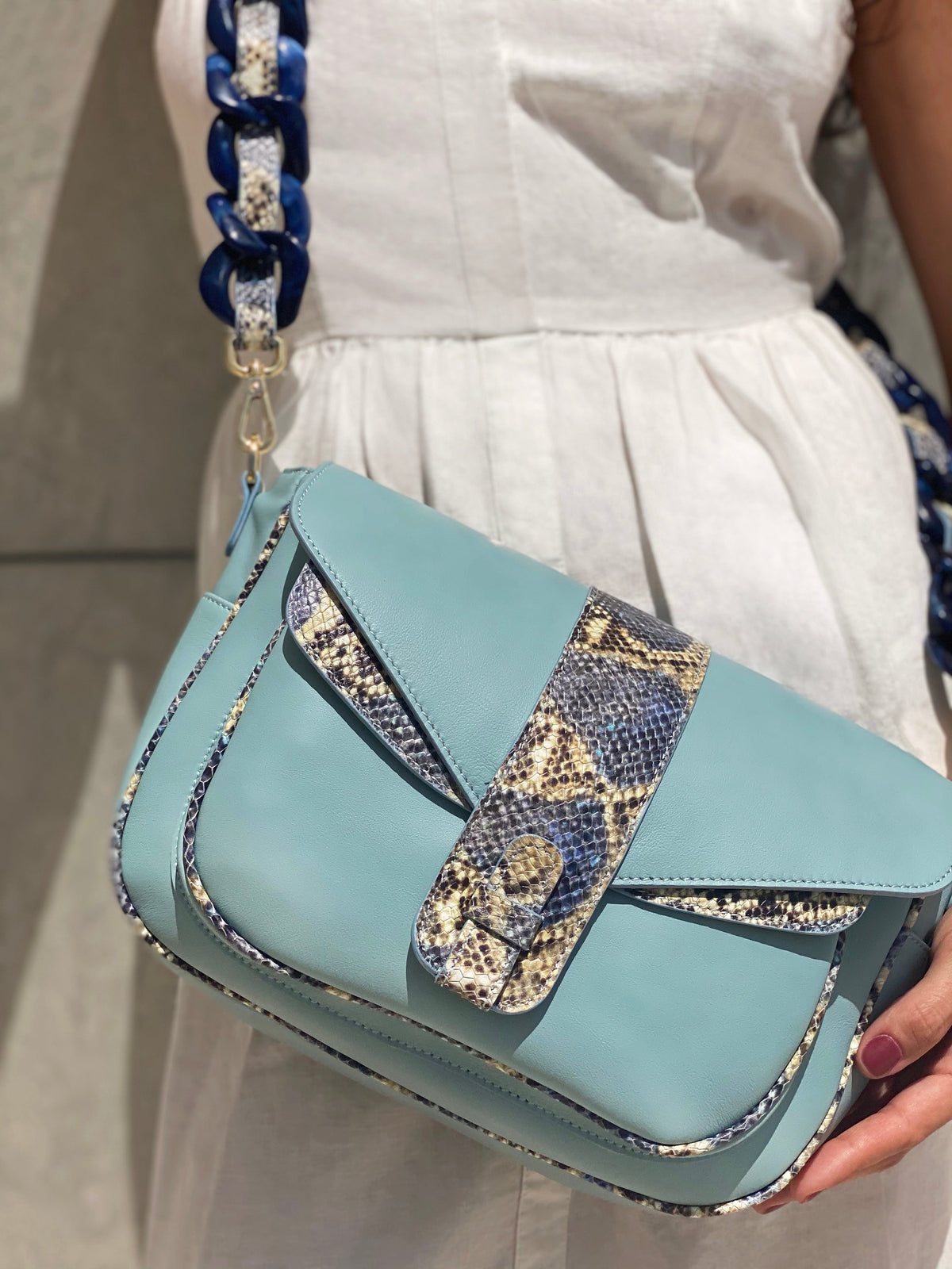 Ximena Kavalekas Kara blue leather crossbody bag with sleek design and adjustable strap, displayed on a neutral background.
